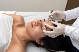 Young woman receiving a dermaplaning treatment at a beauty center, gently exfoliating the skin for a smoother, brighter complexion.