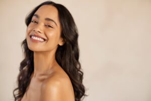 Portrait of laughing mexican girl enjoying beauty treatment isolated on beige background