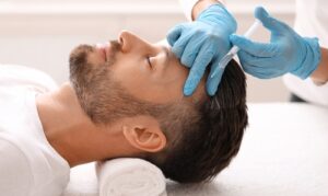 Side view of handsome middle aged man getting hair treatment at beauty salon