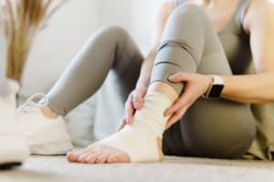 Female athlete holding her ankle in pain after a sports injury, illustrating joint or muscle strain and potential treatment with PRP therapy