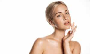 Blond woman touching glowing skin, applying toner or cream for a healthy look after shower, BBL and Moxi treatment