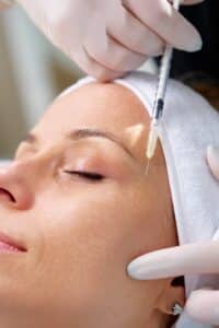 Young woman receiving Botox injection at beauty clinic, close-up medical cosmetology treatment for wrinkle reduction and facial rejuvenation