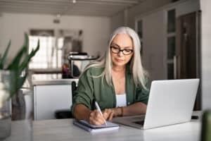 Woman walking through snow in winter clothes enjoying cold weather and nature during winter vacation. Older woman working from home looking focused and energized after trying NAD+ IV therapy